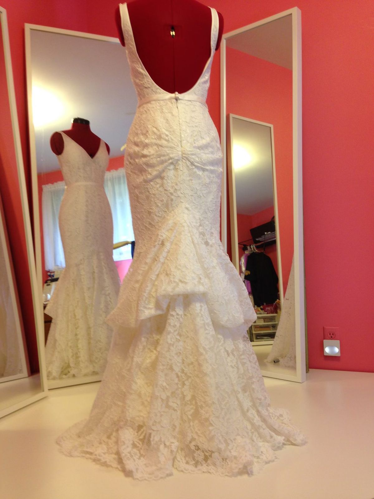The lace back of a mermaid wedding gown with a bustle, on a dress form